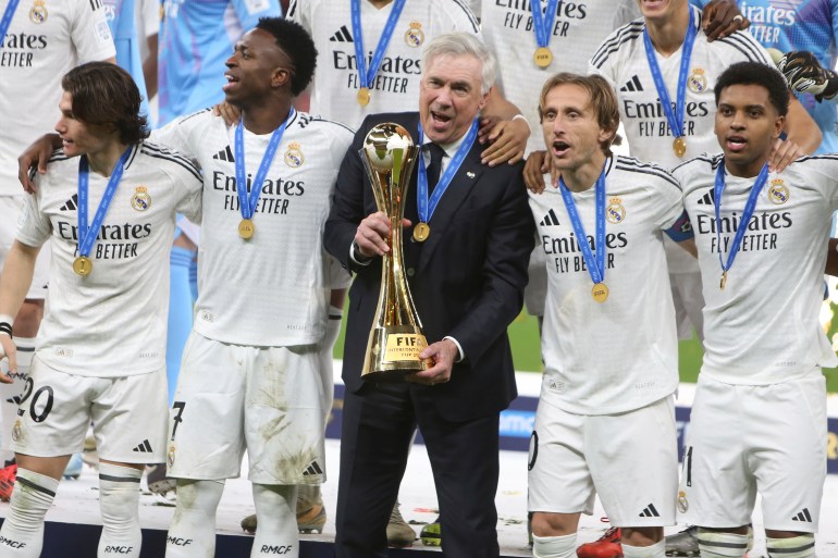 Real Madrid's head coach Carlo Ancelotti, center, pose with the trophy after winning the Intercontinental Cup soccer final match against CF Pachuca at the Lusail Stadium in Lusail, Qatar, Wednesday, Dec. 18, 2024. Real Madrid won the game 3-0.(AP Photo/Hussein Sayed)